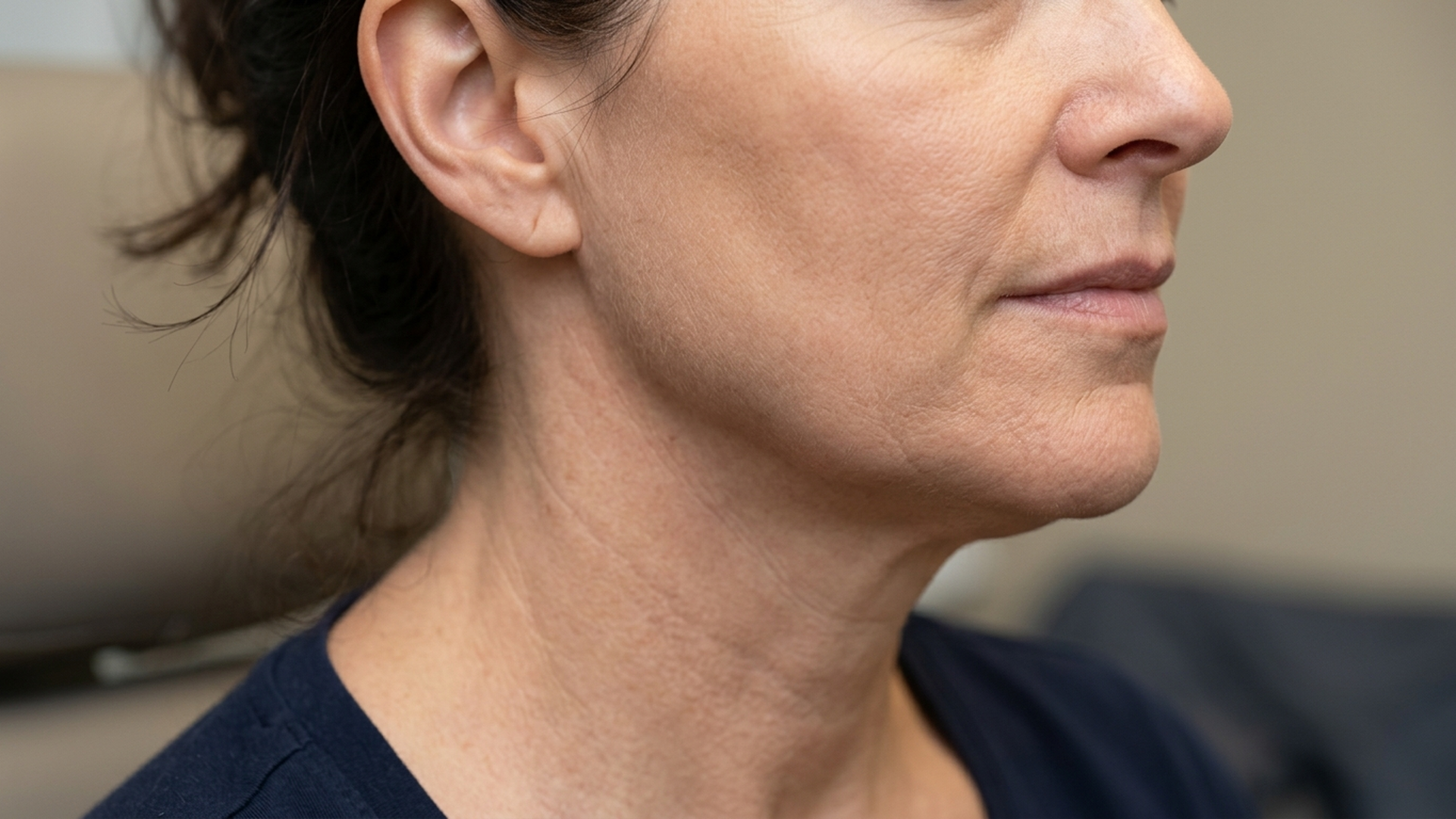 A surgeon discussing the differences between a mini facelift vs deep plane facelift with a patient in a clinic.